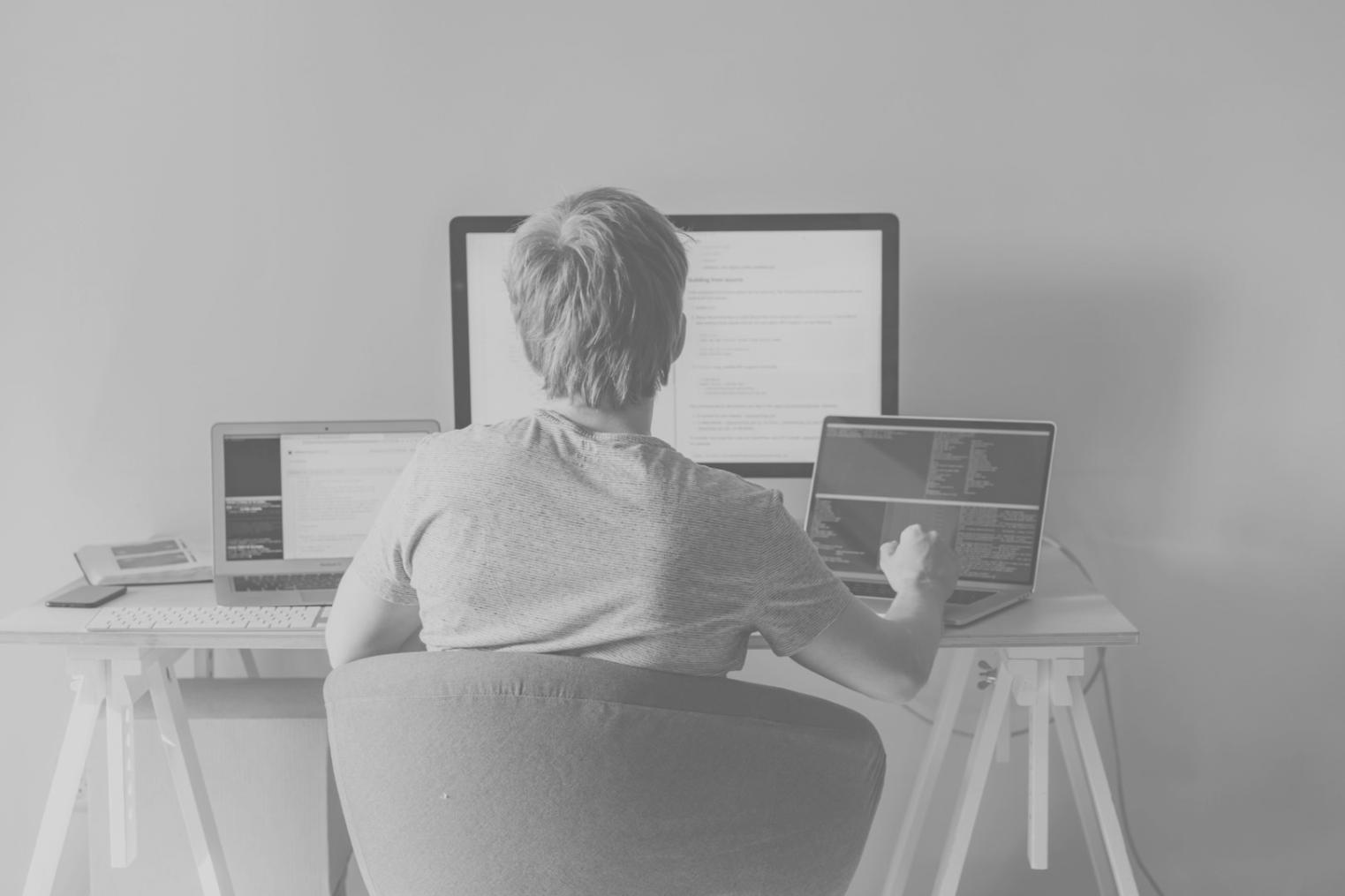 Modern office workspace with multiple screens showing code and app interfaces
